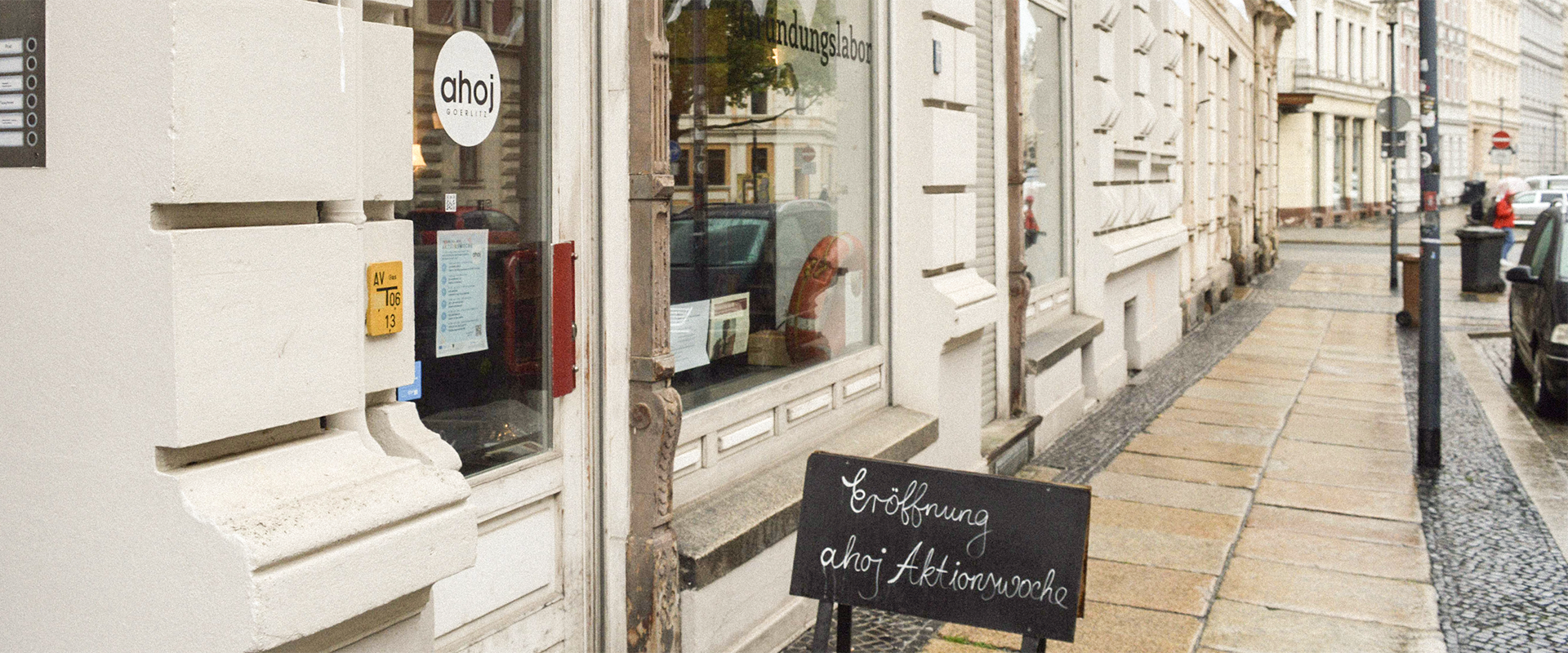 Eingang des AHOJ-Ladens in Görlitz mit Kreidetafel zur Eröffnungswoche vor der Tür.